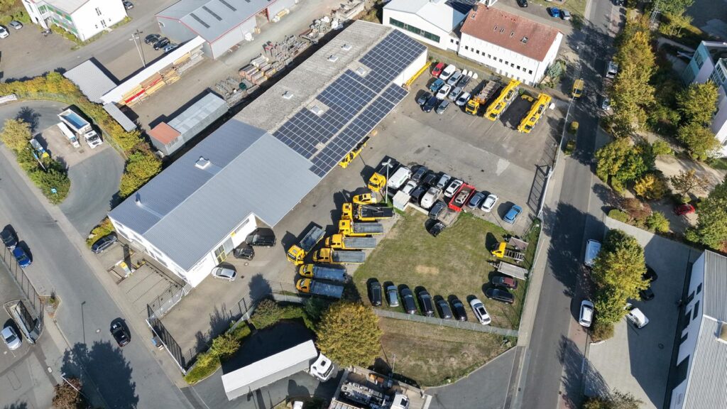 Luftbild des Betriebsgeländes von Kran-Burgard mit Halle, Abschleppfahrzeugen und Verwahrflächen für Pkw und Lkw