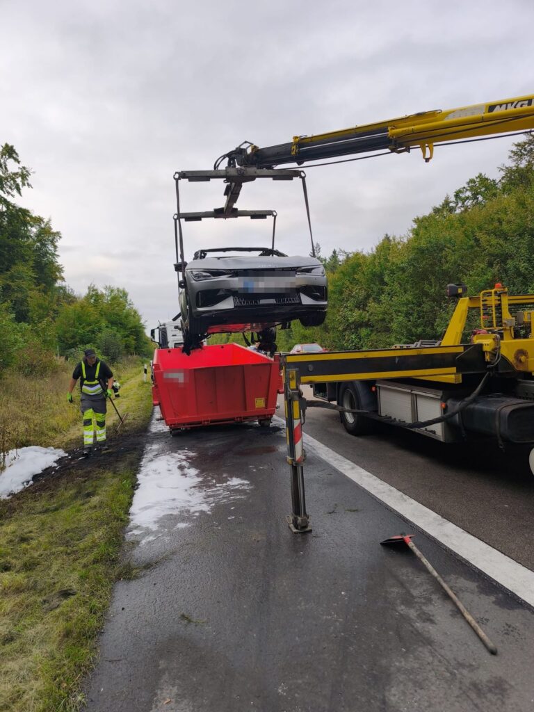 Bergung eines Elektroautos in den Löschcontainer an der Autobahn