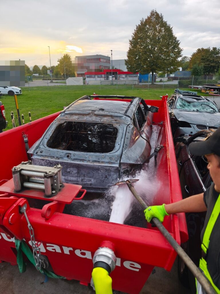 Brandbeschädigtes Elektroauto im Löschcontainer von Kran-Burgard