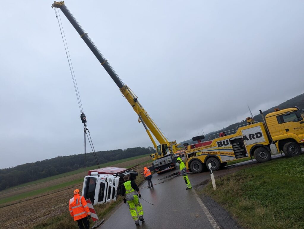 Autokran hebt ein verunfalltes Fahrzeug aus dem Graben