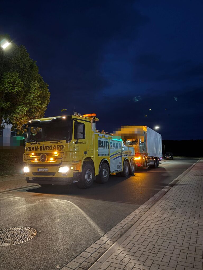 Lkw-Abschleppdienst bei Nacht: Bergefahrzeug von Kran-Burgard mit abgeschlepptem Lkw